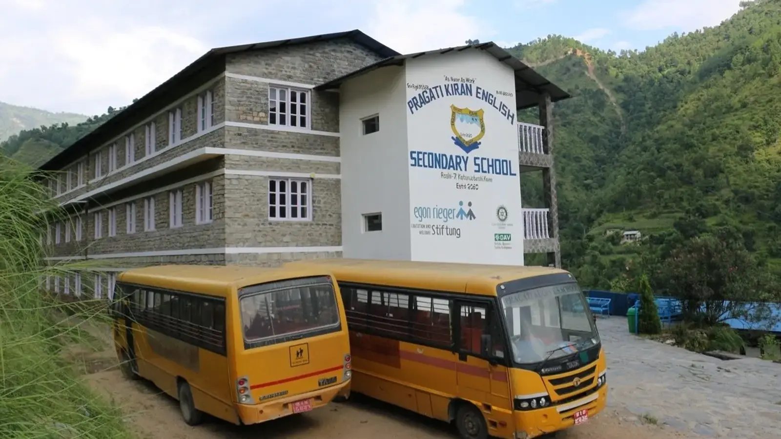 Schulgebäude mit zwei Schulbussen