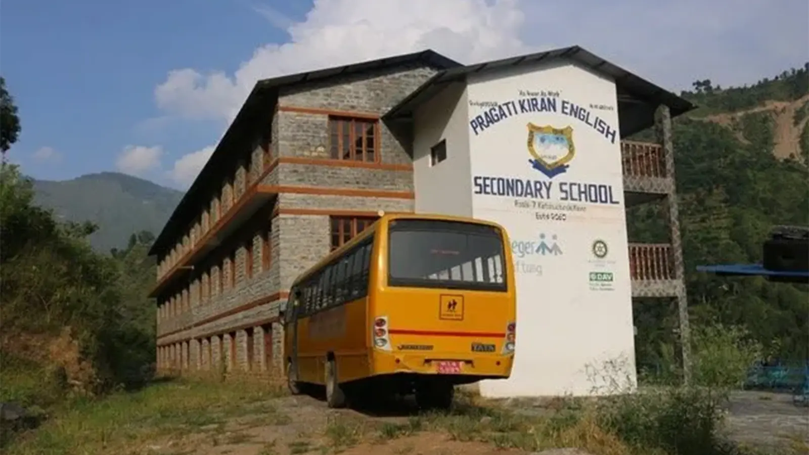 Schulgebäude mit einem Schulbus davor